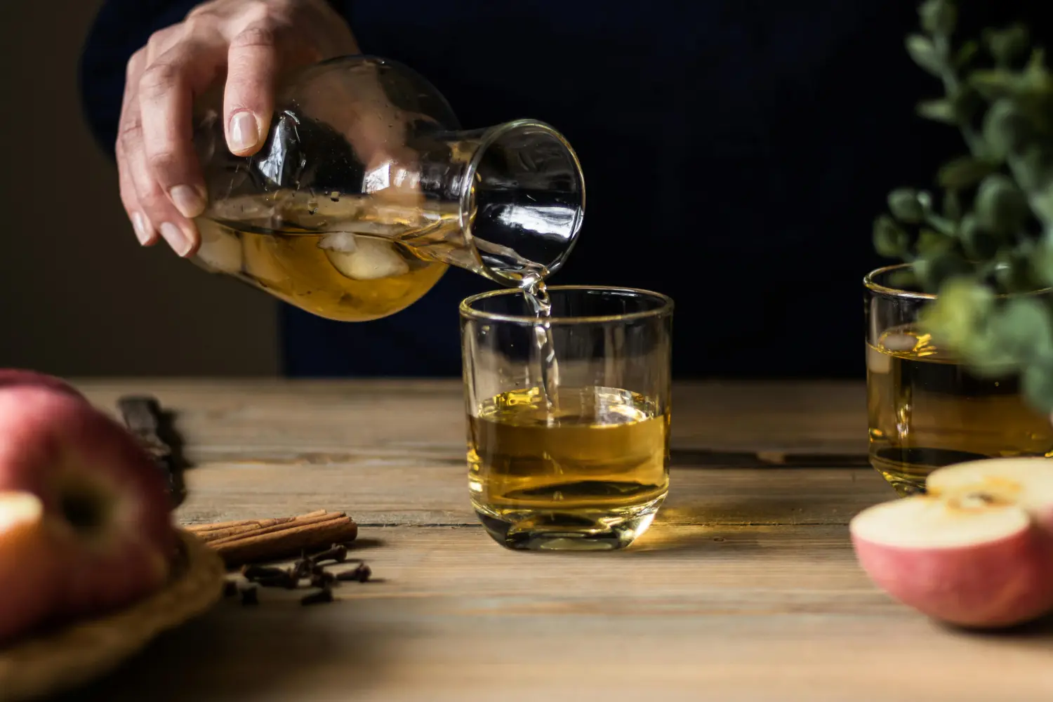 Přelévání jablečného cideru do sklenice s ovoce a kořením