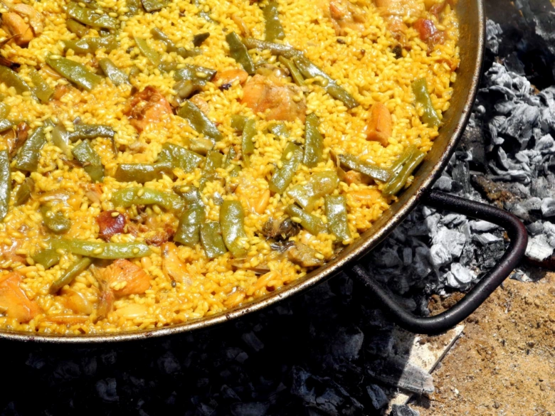 Španělská paella s rýží, zeleninou a masem na uhlích