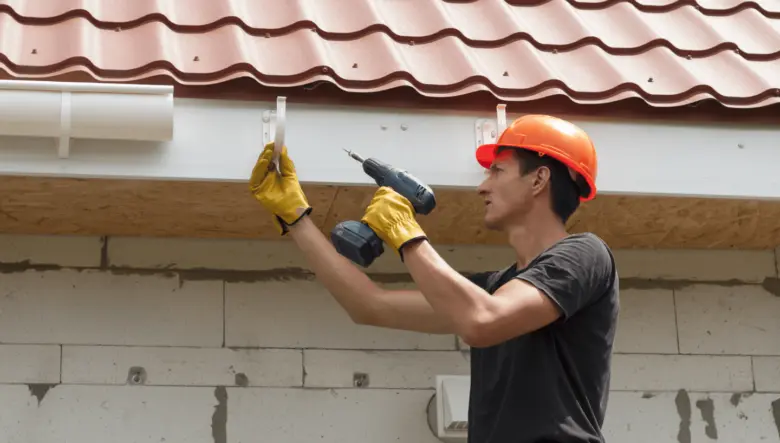 Muž montuje okapové držáky pomocí vrtacího nástroje