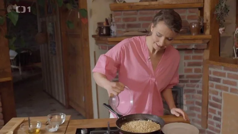 Žena připravuje pučálku z cizrny na pánvi v kuchyni.