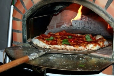 Pizzová pečící trouba s hořícím dřevem a pizzou na kladivu
