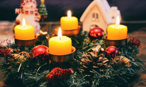 Adventní věnec s čtyřmi zapálenými svíčkami a vánočním ozdobením