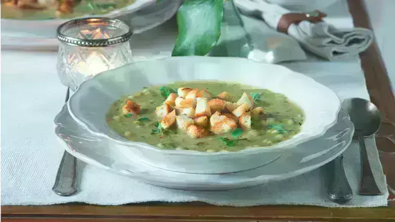 Luxusní hrachová polévka s chlebíčky na bílém talíři