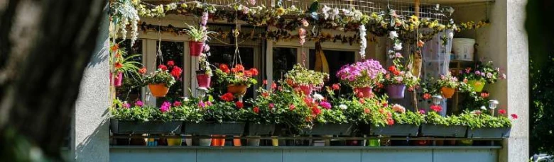 Balkon s květinami převislými v květináčích a závěsných koších