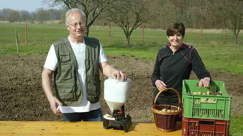Muž a žena s bramborami a nástroji na poli