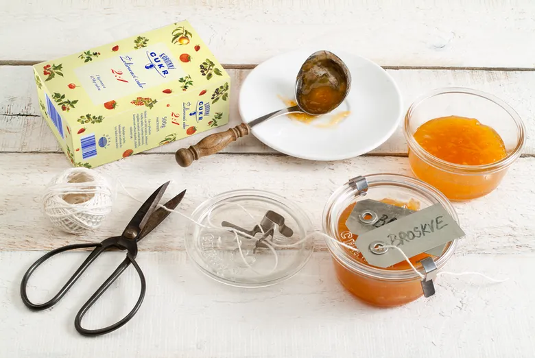 Domácí broskvová marmeláda s ingrediencemi na bílém dřevě.