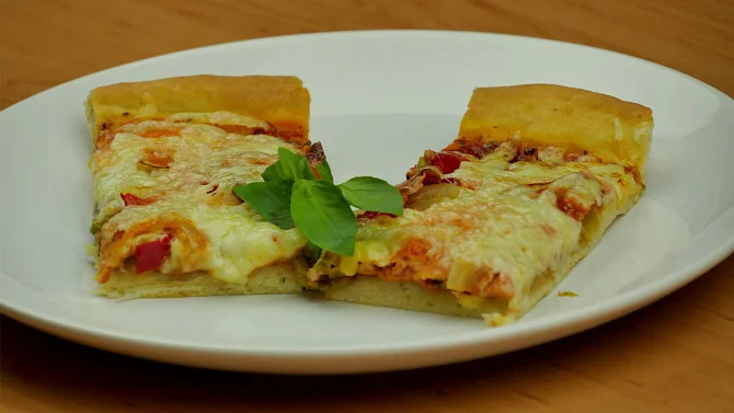 Kousky pizzy bez droždí s sýrem a bazalkou na talíři