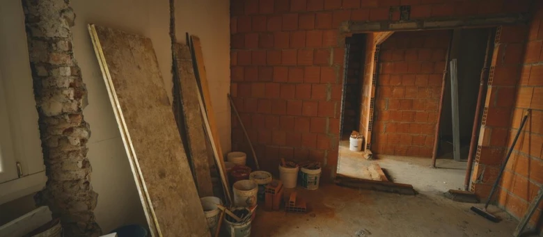 Rekonstrukce domu - nezakončený pokoj s cihlovou zdí a stavebním materiálem