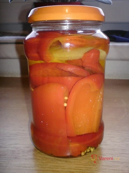 Zavařené papriky v sklenici s oranžovou víčkem.