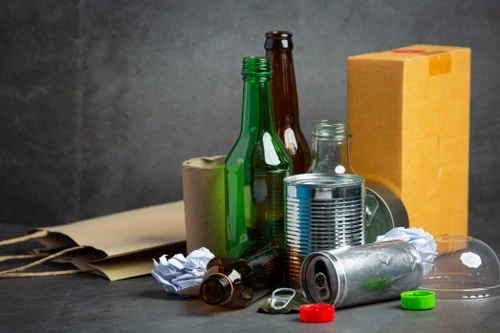 Skleněné lahve a recyklovatelné materiály na tmavém pozadí.