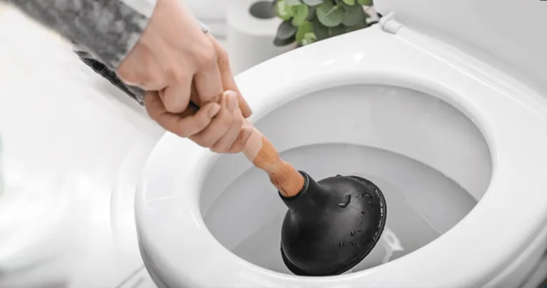 Osoba čistí záchod kbelíkem