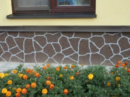 Dekorativní sokl domu s kamenným vzorem a květinovou záhonem