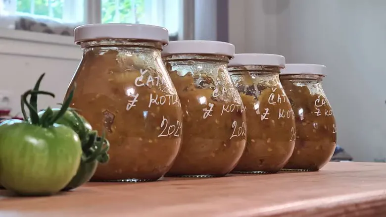 Skleněné lahve s chutným zelených rajčat, vedle čerstvá zelená rajče