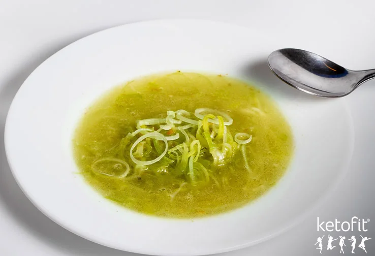 Dietní zelená polévka s cibulí na bílém talíři