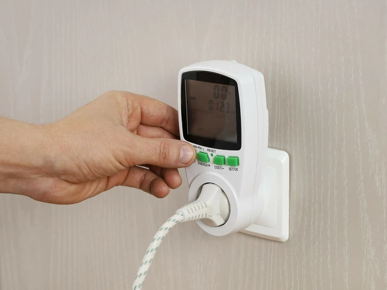 Ruka zapíná elektrický měřič do zásuvky