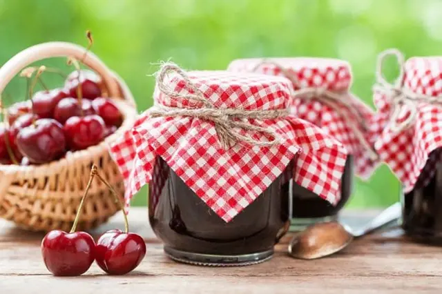 Sklenice s třešňovou džemem a košík čerstvých třešní