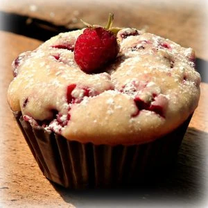 Kefírový muffin s jahodami posypaný cukrem pudrem.