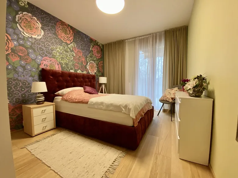 Ložnice s květinovou tapetou a červeným postelem