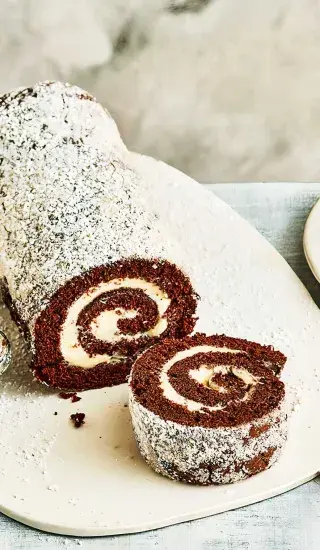 Kakaová roláda se šlehačkou, nakrájená, posypaná práškovým cukrem