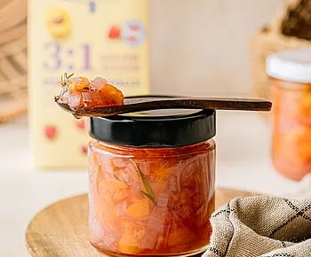Domácí broskvová marmeláda v sklenici s lžící