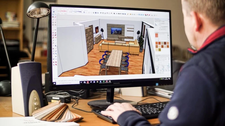 Muž navrhuje interiér domu pomocí 3D návrhového softwaru na počítači