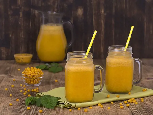 Mražený rakytník v sklenicích s trubičkami, na dřevěném stole