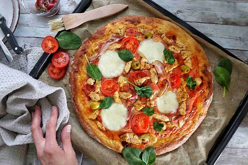 Dokonale pečená pizza s rajčaty, šunkou a bylinkami
