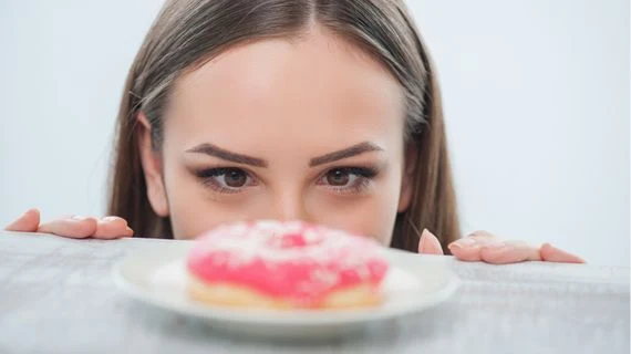 Žena se dívá na růžový donut s cukrovou polevou
