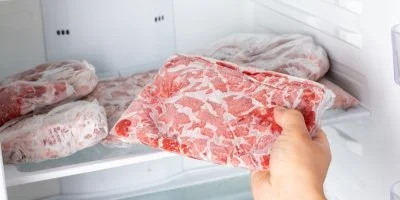 Ruka vybírá zamražené maso z mrazáku