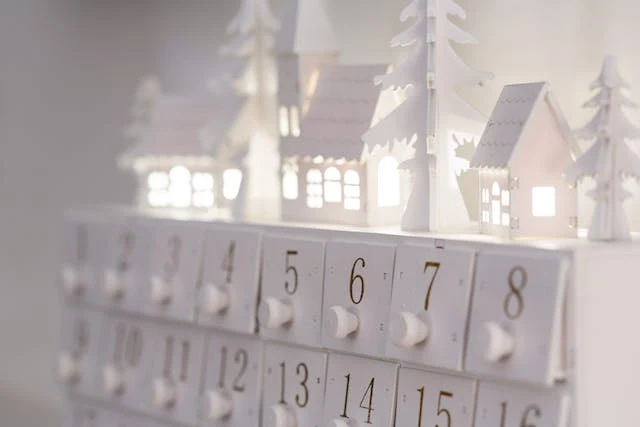 Bílý adventní kalendář s domečky a stromky