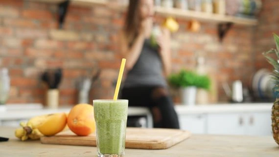 Zelený smoothie s banánem a pomerančem na kuchyňském stole