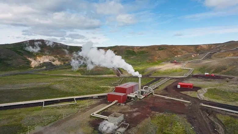 Geotermální elektrárna s výfukem páry na vulkanické krajině.