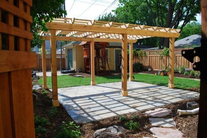 Dřevěná pergola nad kamennou terasou v zahradě