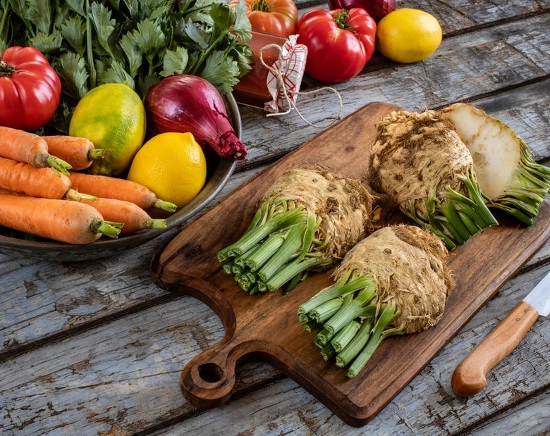 Celeriac na dřevěné desce s dalšími zeleninami