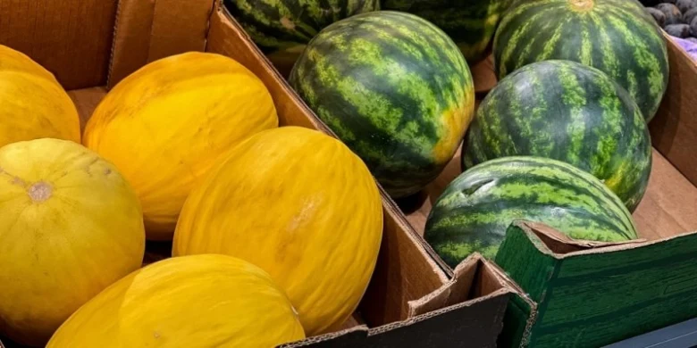 Žluté a zelené melouny v krabicích na trhu