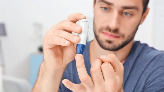 Muž měří hladinu cukru v krvi pomocí glukometru