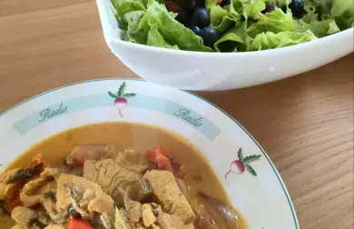 Hot duck soup in white bowl next to fresh salad.