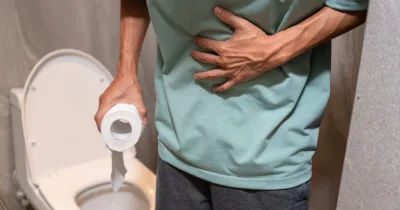 Muž s bolestí břicha u toalety, drží toaletní papír