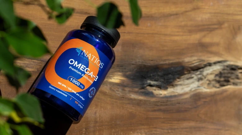 Modrá lahvička s doplňkem omega-3 na dřevě.