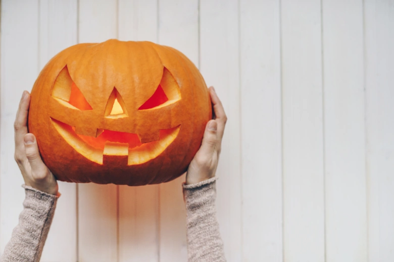 Carved pumpkin with hands holding it