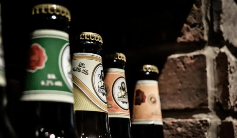 Tmavé skleněné lahve piva s viditelným obsahem alkoholu na etiketách.