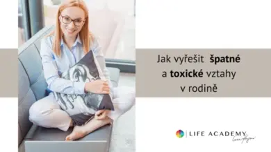 Žena sedí na gauči s polštářem a notebookem v domácnosti.
