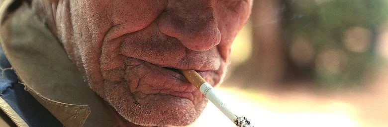 Starší muž kouří cigaretu, ilustrace rizikového faktoru pro rakovinu hrtanu.