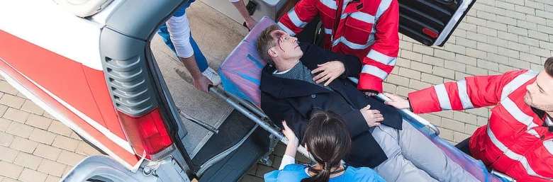 Záchranáři nosí zraněného pacienta do sanitky.
