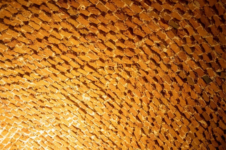 Detail textury zdivého klenutého stropu s malými cihlami.