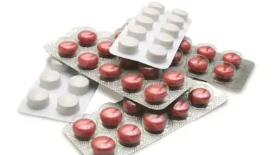 Různé tablety antibiotik v bublinkových obalech na bílém pozadí.