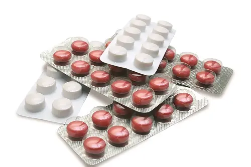 Různé tablety antibiotik v bublinkových obalech na bílém pozadí.