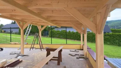 Stavba dřevěného altánu s viditelnými trámy na zahradě.