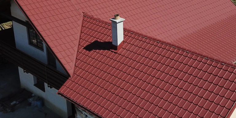 Červená střecha s komínem ukazuje správné oplechování.