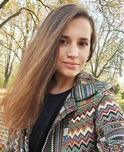 Mladá žena stojí venku v parku s lesy na pozadí.